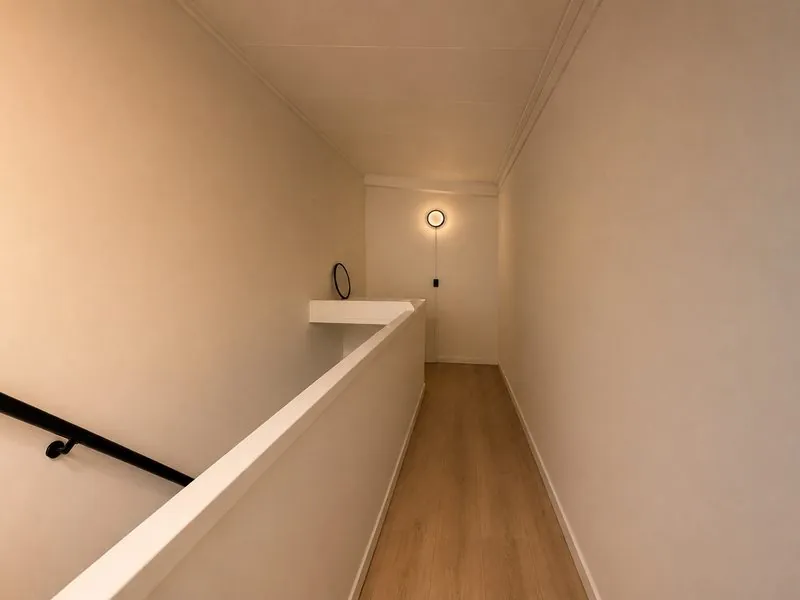 Spiegelglad afgewerkte wanden op een overloop met houten vloer