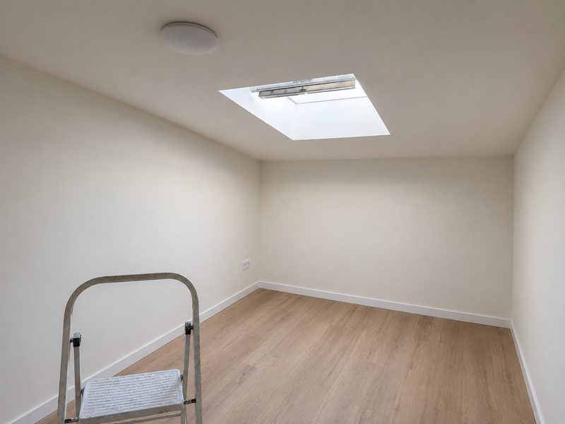Strak gestuukt plafond in een zolderkamer met dakraam
